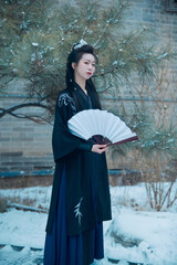 A Chinese girl dressed in Hanfu plays a martial arts hero in the snowy ancient city