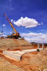 Fototapeta premium Yellow Crane Operating Beside Culvert Construction Site