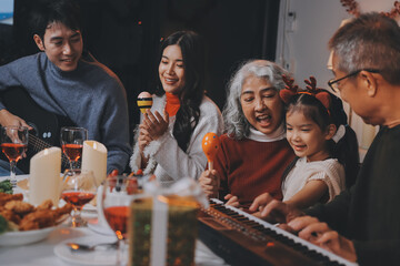 Multi-Generation Family Celebrate Christmas At Home Wearing Santa Hats And Antlers Opening Presents