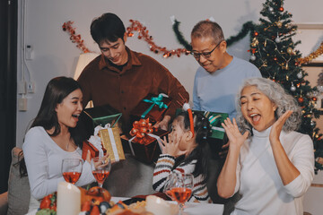 Portrait of Asian family exchanging presents during christmas at home. Attractive happy people holding gift box, celebrate holiday thanksgiving, xmas eve tradition in living room in house together.
