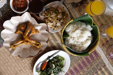 fried chicken, liwet rice, fresh vegetables, plate, stir-fried water spinach, chili sauce, orange juice. various Indonesian dishes. lunch dishes. ayam goreng, sambal, lalapan.