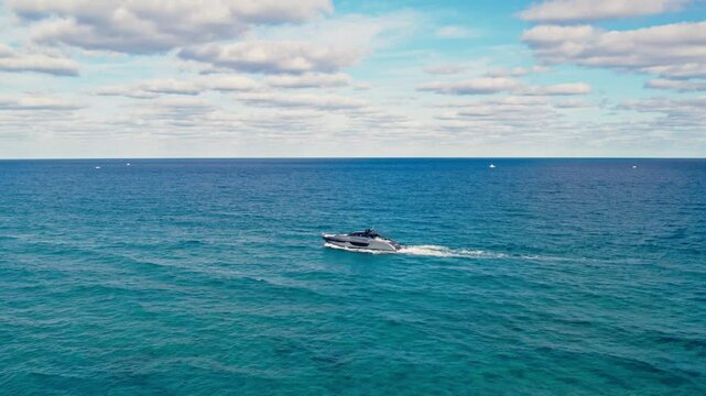 Drone push in tp clear blue ocean waters stretching toward the horizon with yacht driving across at West Palm Beach Florida USA