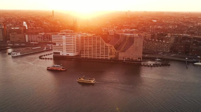 amsterdam city skyline with boats going by during a stunning sunset