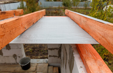 A wooden beam with a grey plastic sheet on top of it