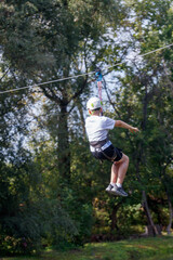 A man is jumping on a zip line in a forest
