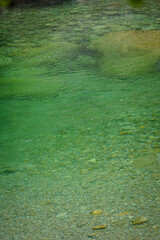 Turquoise mountain river water with stones and rocks being visible under the water, Switzerland