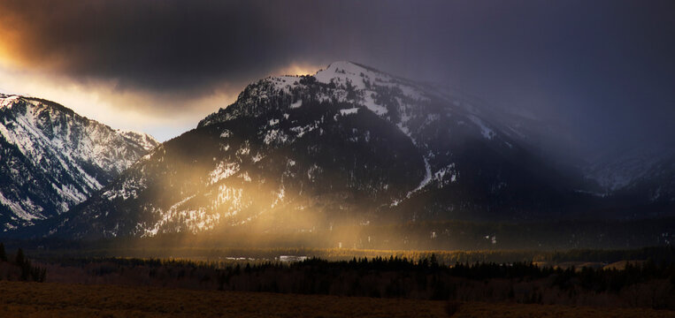 Sunset breaks through a snow storm in the Grand Tetons National Park.