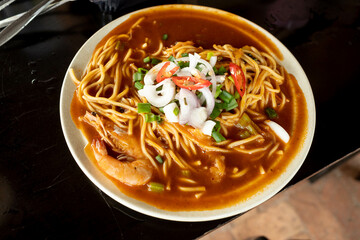 A plate of Malay prawn noodles being served with fresh prawns filled with tomato based soup in Malaysia