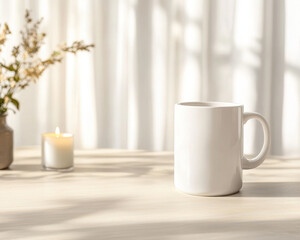 White blank mug mockup on a table, in a minimalist modern room with sun rays and shadows. The blurred background includes a vase of flowers and a candle in a glass jar, white curtains.
