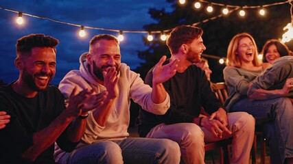 Friends enjoying a joyful evening around a fire pit with string lights at a backyard gathering