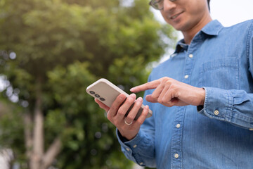 close up young asian man hand hold mobile cell phone device to play social media or read news...