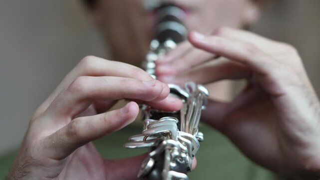 Concentrated male musician solo playing clarinet with passion, soft focus on fingers. Maser class in music, male practicing woodwind skills, wind instruments lesson