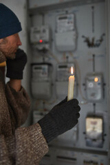 Checking the electricity power meter with a candle in cold winte