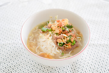 Indonesian beef soto soup served with steamed rice, bean sprouts in a small white bowl. Perfect for breakfast & lunch