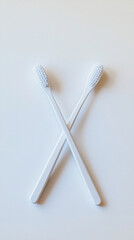 Two toothbrushes crossed on a white surface