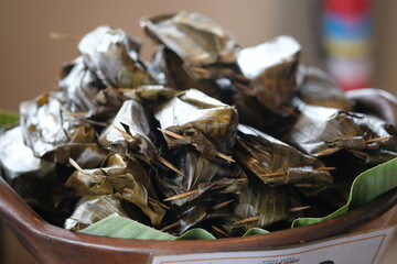 Pepes tahu wrapped in banana leaves in a pottery container. Indonesian food.