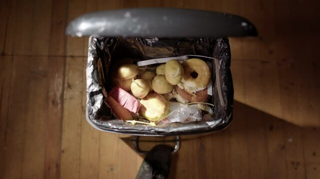 Top POV of expired vegetables being thrown away into black garbage bin