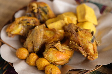 chicken, tofu, tempeh and fried quail eggs. side dishes in a traditional plate. Indonesian food.