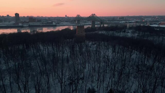 aerial shot over Jean Drapeau Park in Montreal Coty revealing the Jacques Cartier Bridge and the skyline with the levis tower in the foreground at sunset, quebec province, Canada