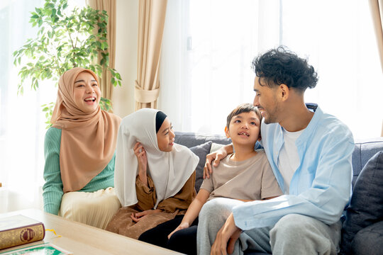 Asian muslim famity with mother, father, boy and girl stay relax together on sofa in living room of their house in concept of happy muslim family at home.