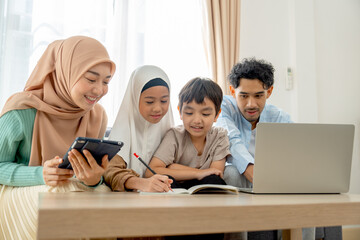 Little Asian muslim girl use pencil to write on notebook to play with her younger brother and...