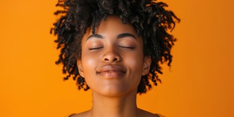 Joyful woman deep in thought, smiling against an orange backdrop. Reflecting, using emojis, with a positive mindset, making decisions in a creative studio environment