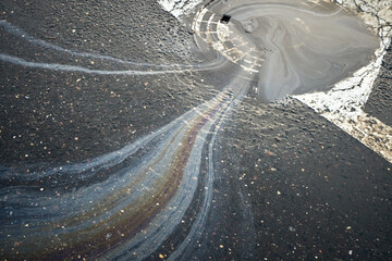 Colorful gasoline or oil spill polluting a wet asphalt road surface