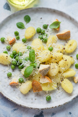 Italian gnocchi served with different types of cheese and green peas on a white plate, vertical shot, middle close-up, selective focus