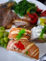 Delicious salmon nigiri and maki sushi with roe and sesame seeds on white plate all you can eat