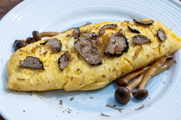 French omelette with mushrooms, fresh farmers eggs and black summer truffle mushroom in pieces for making truffle dishes with tasty aroma
