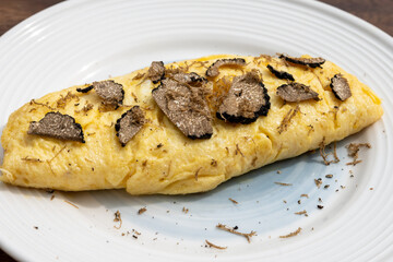 French omelette with mushrooms, fresh farmers eggs and black summer truffle mushroom in pieces for making truffle dishes with tasty aroma