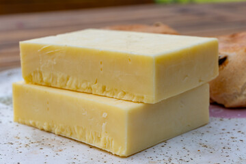Block of aged cheddar cheese, the most popular type of cheese in United Kingdom and USA, natural cheese from cow milk
