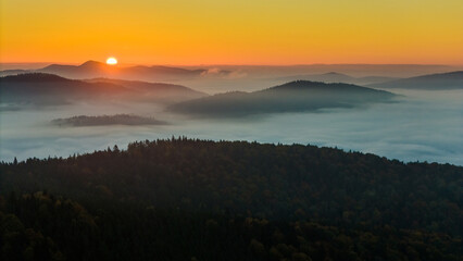 Aerial drone view of sunrise above clouds in mountains