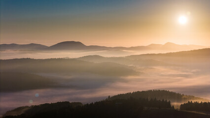 Aerial drone view of sunrise above clouds in mountains