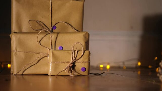 Gift wrapped in brown paper and string with Christmas lights bokeh background