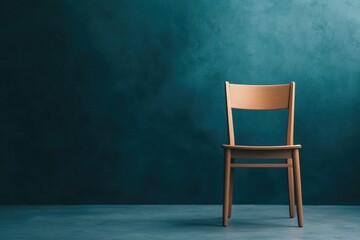 simple wooden chair stands alone against teal wall, evoking solitude