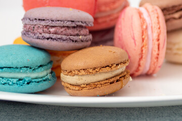 Close up delicious macaroon cookies in fresh mint green vanilla beige chocolate brown orange and...