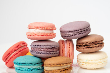 Close up delicious macaroon cookies in fresh mint green vanilla beige chocolate brown orange and pink colors. Light white background. Contrast bright combination, bakery culinary.