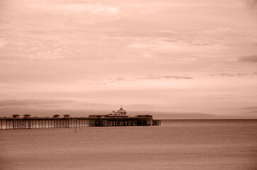 Mocha Mousse toning, color of the year 2025. Seaside landscape with pier, England, UK. Minimalistic seaside landscape with the pier, sunset or sunrise in pastel colors. High quality photo