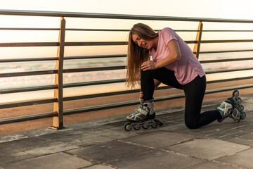 Athlete feeling knee pain after falling while inline skating near the beach copyspace