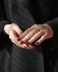 Young woman's hands and fingers with simple modern creative nail manicure with black winter clothes with gold ring _ Woman's hands with nail polish 