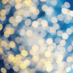 Fototapeta premium Abstract bokeh background with blurred white and yellow lights against a deep blue backdrop, creating a festive and dreamy atmosphere.