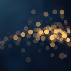 Abstract bokeh background with blurred white and yellow lights against a deep blue backdrop, creating a festive and dreamy atmosphere.