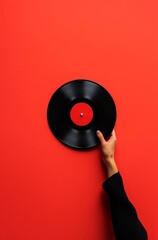 a hand holding a vinyl record, against a solid red background