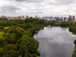 aerial view of Ibirapuera Park in Sao Paulo city with cloud sky, lake, and the city skyline