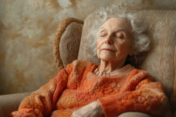 Elderly woman peacefully sleeping in a comfy armchair, eyes closed, wearing an orange sweater.