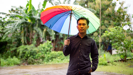 Man using rainbow multi-colored umbrella during drizzle