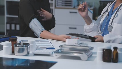 Male doctor uses a blood pressure monitor to check the body pressure and pulse of the patients who come to the hospital for check-ups, Medical treatment and health care concept.