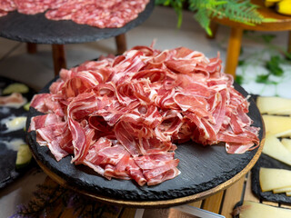 Plate with slices of jamon iberico traditional spanish ham in restaurant buffet close up