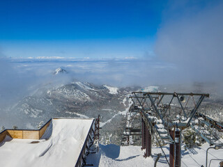 Chairlift at the summit of ski resort and sea of clouds covered the below clearing away (Yokoteyama, Nagano, Japan)